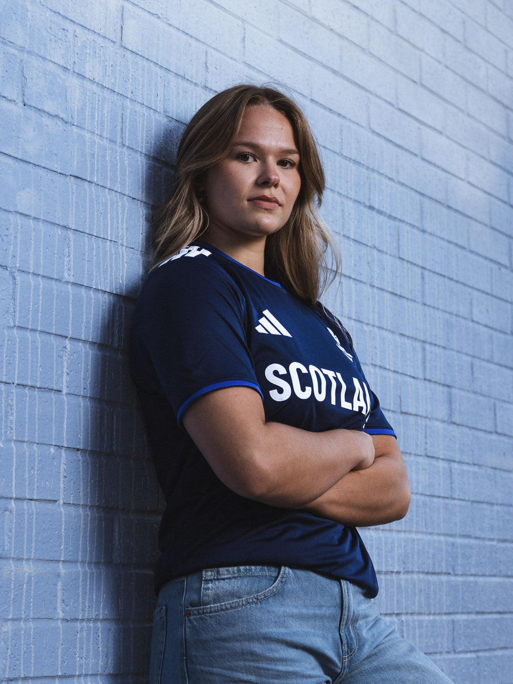 Three quarter view of woman wearing navy adidas Team Scotland Saltire Jersey.