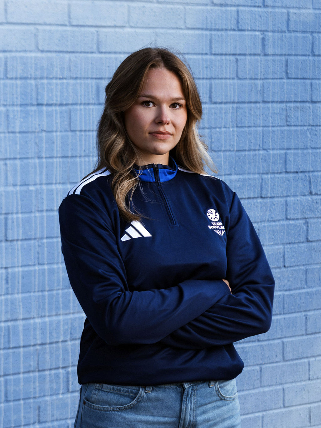 Front view of woman wearing navy three quarter zip adidas Team Scotland track top.